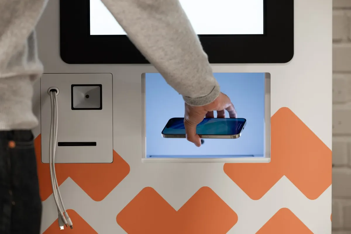 Hand som lägger en iPhone i en Vendy-kiosk